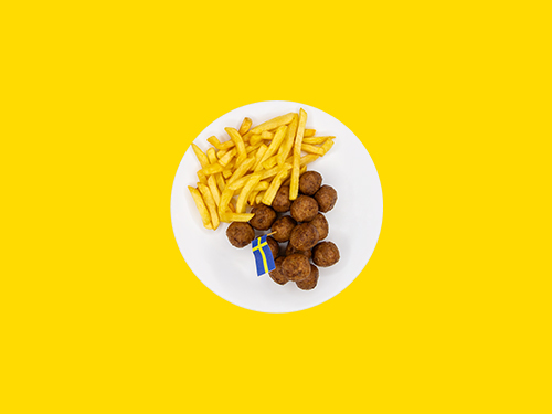 Plato con albóndigas suecas y papas fritas sobre fondo amarillo brillante.