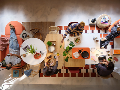 Top view of people relaxing, eating, and working at tables in a shared space.