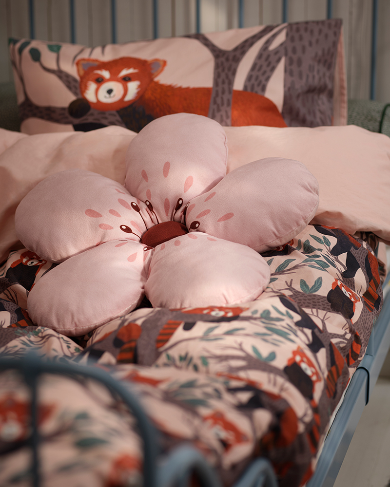 A pink flower ALPTALL cushion on ALPTALL bedding in a child’s bedroom.