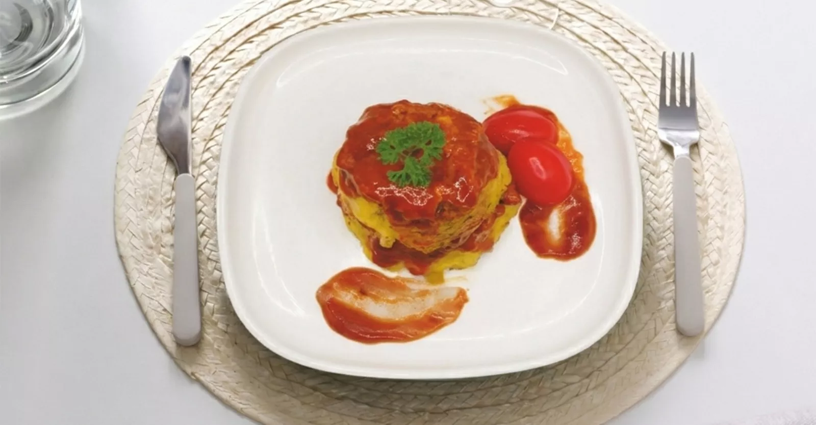 Plato con timbal salado cubierto de salsa de tomate y tomates cherry.