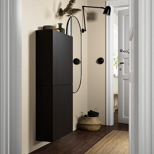 Mueble de almacenamiento BESTÅ negro, delgado y alto, montado en la pared junto a la cesta tejida y la lámpara de pared.
