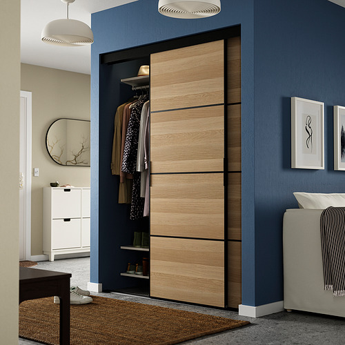 Dormitorio moderno gris con armario gris, parcialmente abierto, entre espejo y cama.