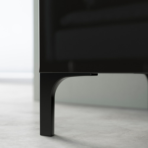 Las patas de metal negro elevan un mueble de televisión. Diseño minimalista, soporte fuerte y fácil limpieza.