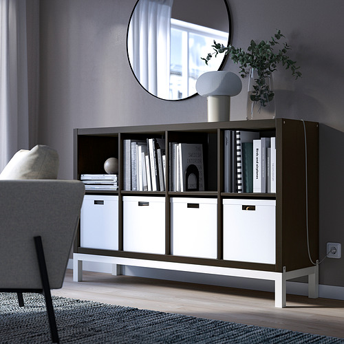 Estantería KALLAX negra con papeleras blancas, libros, espejo y silla.