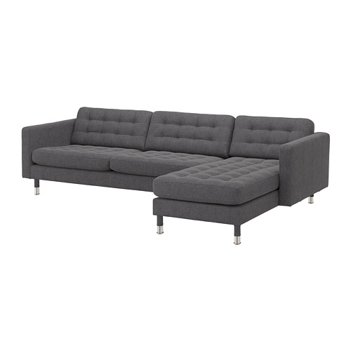 Moderno sofá gris en forma de L con patas oscuras y cojines capitoné.