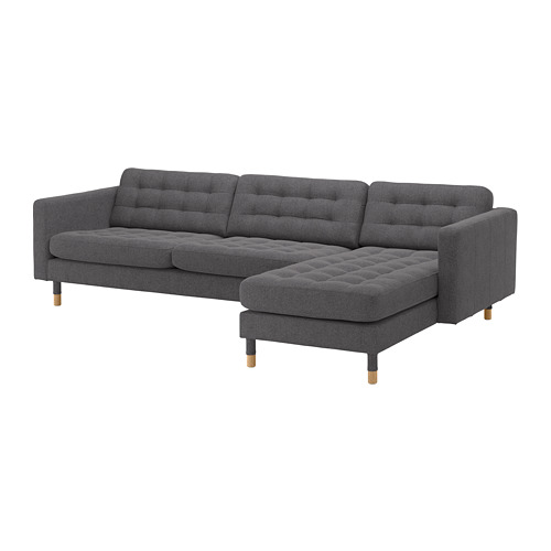 Moderno sofá seccional gris en forma de L con cojines capitoné, patas de madera oscura y diseño elegante.