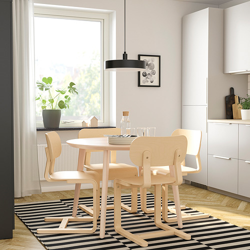 Un comedor moderno con una mesa de madera, sillas, lámpara colgante negra y una planta junto a la ventana.