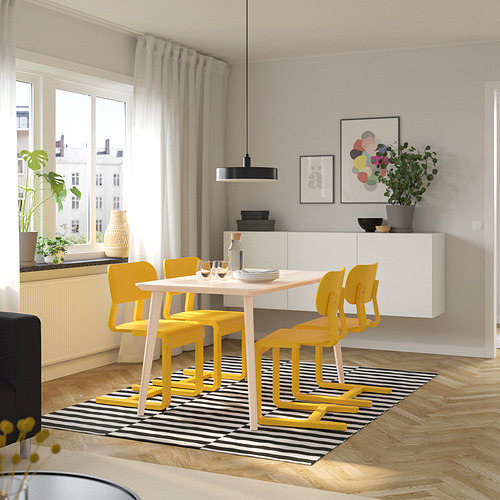 Luminoso juego de comedor con sillas amarillas, de diseño moderno, colocado bajo un gran ventanal, que complementa la mesa blanca y las decoraciones de pared.