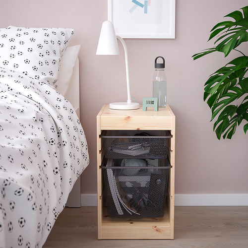 Mesa auxiliar de madera TROFAST cerca de cama con temática de fútbol, lámpara de sostenimiento, botella de agua y cestas de malla.