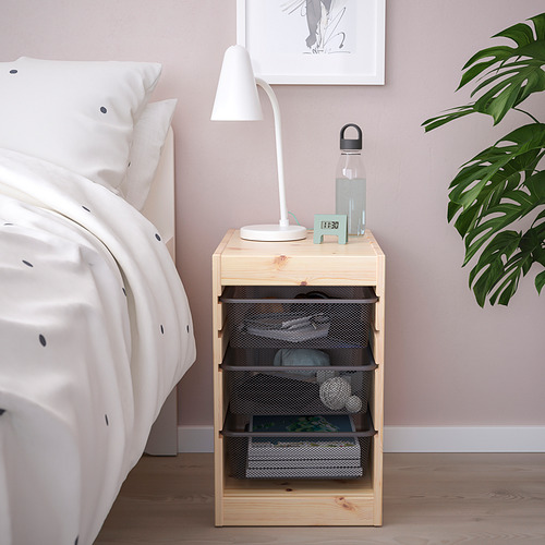 Almacenamiento de madera TROFAST por cama con lámpara, botella y plantas.