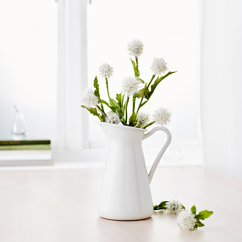 Jarrón blanco con flores blancas, colocado sobre una encimera brillante cerca de una ventana. También funciona como jarra.