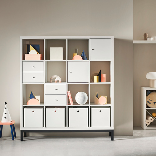 Estantería KALLAX blanca con elementos de decoración de varios colores. Diseño moderno y modular con múltiples compartimentos, cajones y cajas de almacenamiento cerradas.