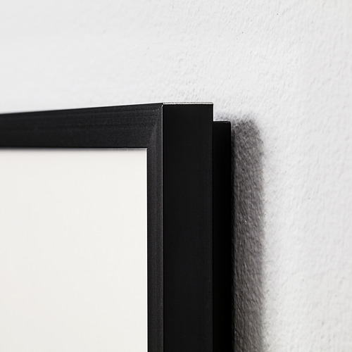 Marco de fotos negro con borde metálico estrecho montado en pared blanca. Acabado de alta calidad, líneas limpias.