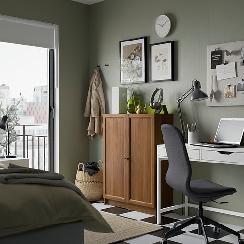 Acogedor dormitorio con librería Billy, escritorio, silla, sábanas verde oliva y pared verde con arte y reloj.
