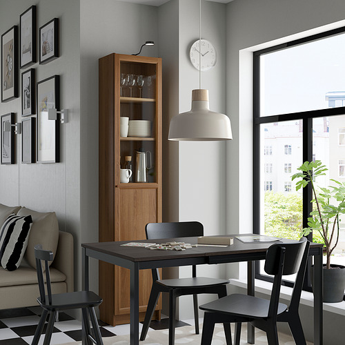 Acogedor comedor con estantería BILLY, sillas negras, mesa y decoración.