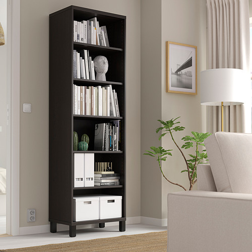 Estantería negra BESTÅ con libros, decoración, por ventana, silla, lámpara, planta.