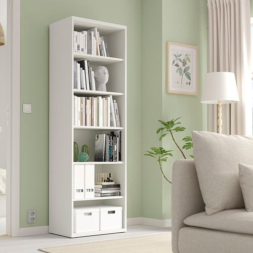 Sala de estar moderna con estantería y decoración BESTÅ. Estante alto, estrecho y ajustable. Sillón beige y lámpara al lado.