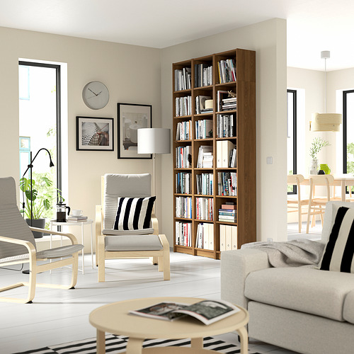 Moderno salón con librería BILLY, sofá gris, sillones y luz natural.