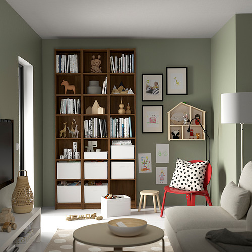 Acogedora sala de estar con estantería BILLY, blanco, alto, de madera, pared verde, sofá blanco, silla roja para niños, arte enmarcado, juguetes y lámpara.