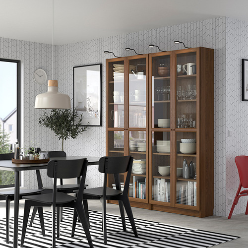 Moderno comedor con librería BILLY, mesa, sillas, planta y lámpara colgante.