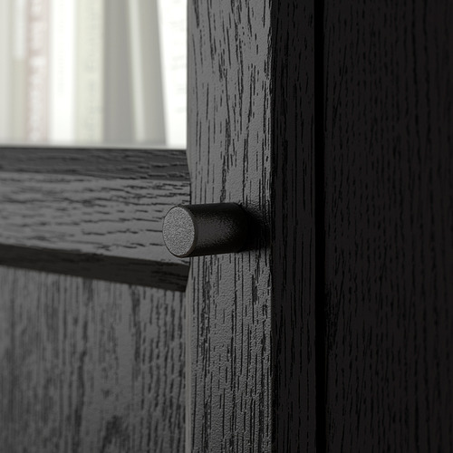 Tirador cilíndrico de metal negro en puerta de madera oscura, con vetas naturales y acabado liso.