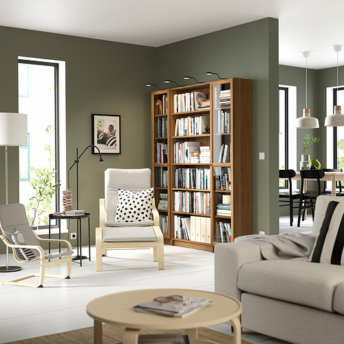 Librería BILLY de madera con puertas de cristal y libros en acogedora sala de estar verde.