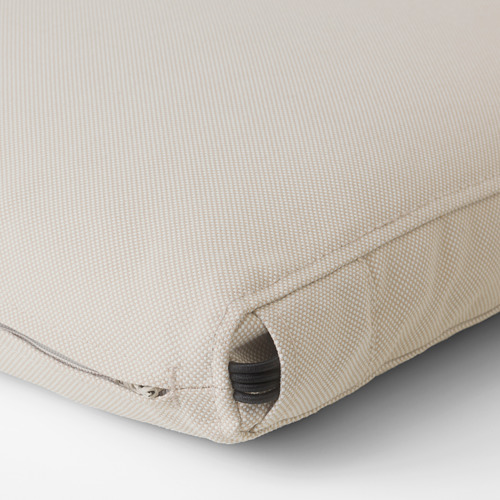 Primer plano de una funda de cojín de exterior beige con cremallera y correa elástica, luciendo un tejido de calidad.