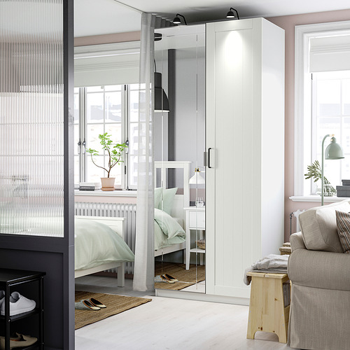 Dormitorio minimalista con gran armario con espejo iluminado entre ventanas.