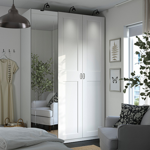 Dormitorio moderno con gran armario PAX blanco, puertas correderas con espejos, lámpara colgante y silla. Incluye cesta de malla y pies ajustables.