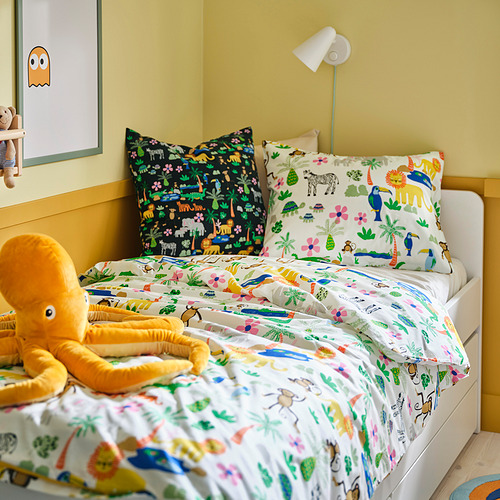 Cama colorida con cojines, pulpo y juguetes de peluche en paredes amarillas brillantes.