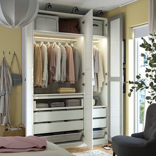 Armario moderno con perchas, cajones e iluminación, que muestra ropa y accesorios cuidadosamente organizados.