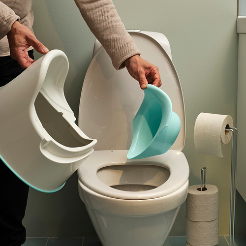 Persona que vierte agua de una jarra blanca en un inodoro blanco con inserto azul, pared verde, rollo de papel higiénico.