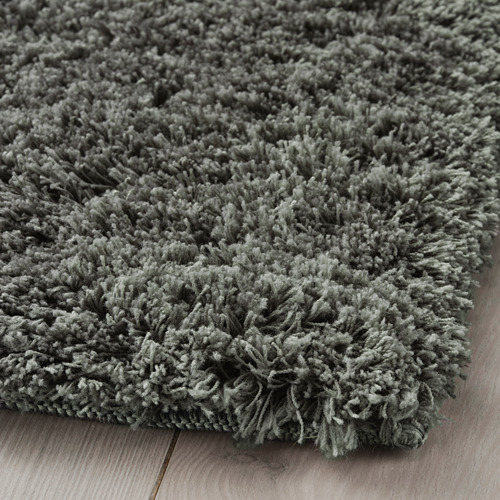 Alfombra de felpa gris con pelo suave y grueso sobre suelo de madera, lavable a máquina, densa para reducir el ruido.