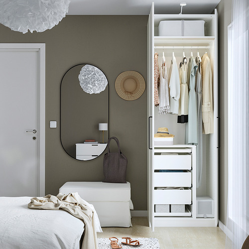 Dormitorio minimalista con armario PAX que muestra ropa organizada, cajones y espacio para colgar. Los espejos y los elementos decorativos realzan la estética de las habitaciones.