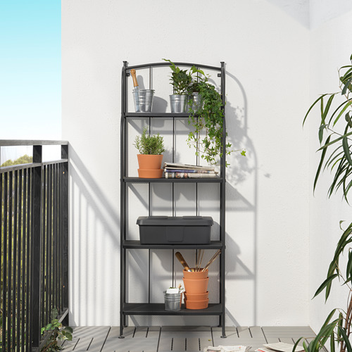 Estantería LÄCKÖ negra con macetas, plantas, herramientas, libros contra la pared blanca.