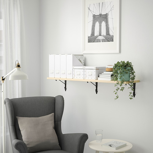Rincón de lectura minimalista: silla gris, estantería flotante con decoración blanca, planta colgante, arte del puente de Brooklyn.