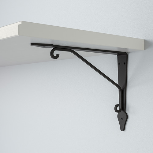 Un elegante estante montado en la pared con un robusto soporte metálico. Estante blanco, soporte negro, montado de forma segura en una pared lisa.