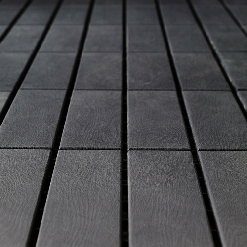 Paneles de terraza de color gris oscuro, perfectamente alineados y espaciados uniformemente, que muestran una textura suave y uniforme, indicativa de un material duradero y de alta calidad.