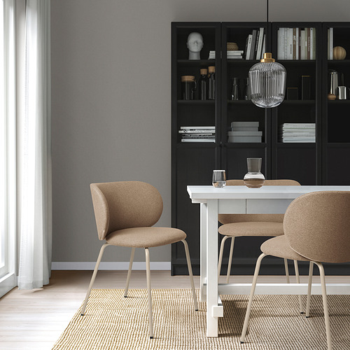 Comedor moderno con sillas KRYLBO alrededor de una mesa blanca. Librería negra con decoración, lámpara colgante de cristal, paredes de color gris claro y suelos de madera clara.