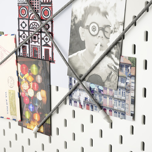 Tablero perforado SKÅDIS con accesorios que sostienen fotos y decoración.