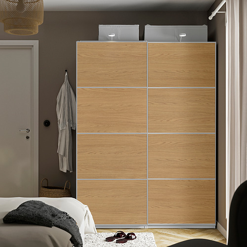 Armario PAX de madera con adornos plateados, puertas correderas, abrigo al lado y cama debajo.
