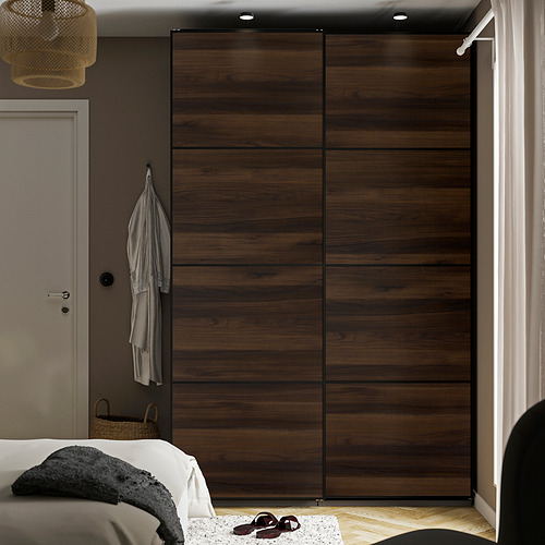 Dormitorio moderno con gran armario corredero de madera marrón, ropa de cama blanca, abrigo colgante y cesta de mimbre.