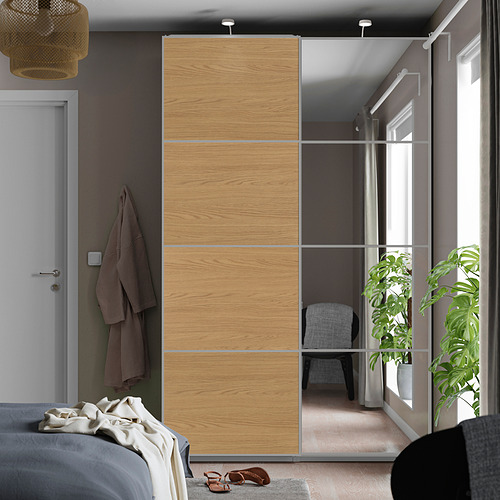 Dormitorio moderno con un gran armario con espejos y una cama con una manta gris y tela marrón.
