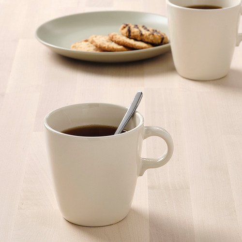 Dos tazas blancas llenas de café, una con una cuchara, y un plato de galletas.
