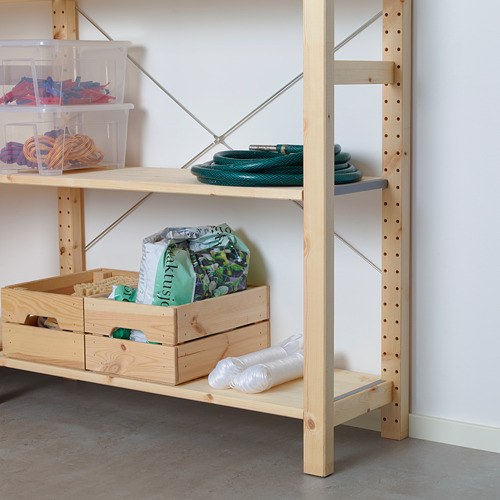 Estantes de almacenamiento de madera clara con recipientes transparentes que contienen artículos coloridos, incluida una manguera verde y bolsas de plástico en el estante inferior.