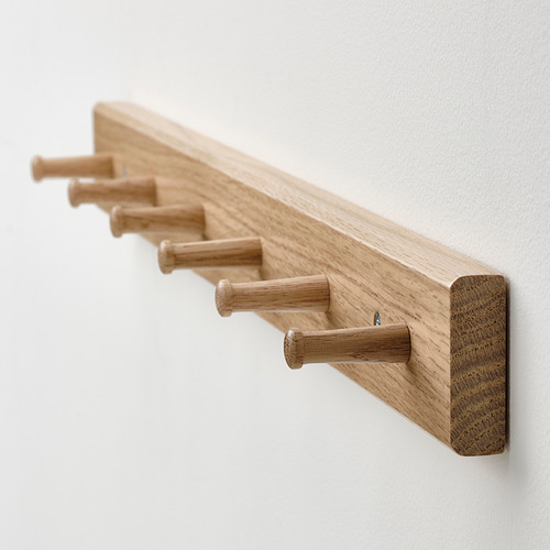 Perchero de madera clara montado en una pared blanca con seis ganchos espaciados uniformemente, que muestran una artesanía suave y de alta calidad.