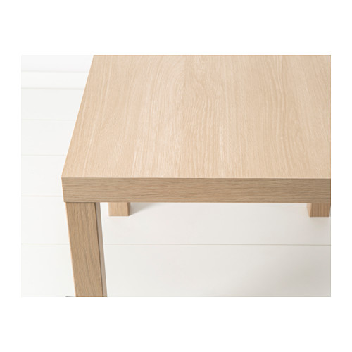 La imagen muestra una mesa auxiliar cuadrada sencilla y moderna con acabado en madera clara y patas delgadas. Diseño minimalista de calidad.