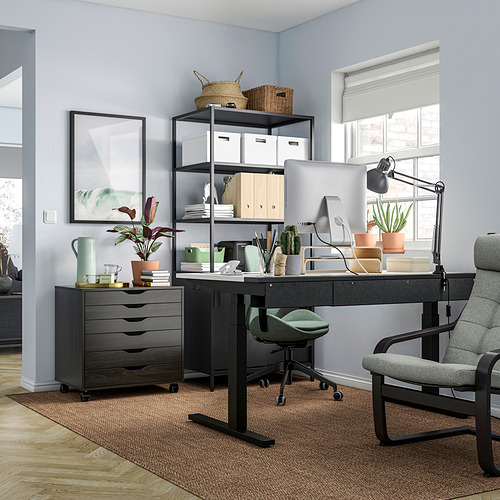 Configuración de oficina en casa: escritorio, silla y unidades de almacenamiento negras, con computadora, plantas y decoración.