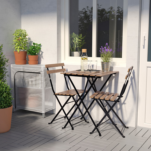 Pequeño juego de mesa de exterior con 2 sillas plegables. Rodeado de plantas en macetas en la cubierta.
