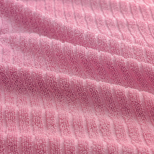 Primer plano de una toalla rosa suave y texturizada, que muestra un tejido grueso y afelpado, que destaca su calidad de algodón absorbente y duradero.